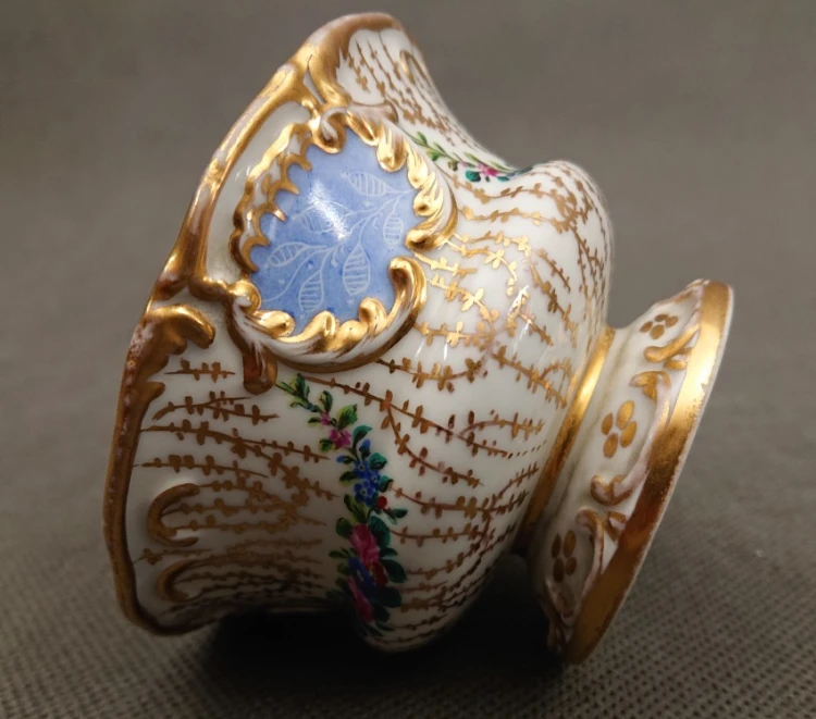Zbliżenie na boczną ściankę porcelanowego naczynia z widocznym precyzyjnym detalem ręcznie malowanej girlandy z kwiatów