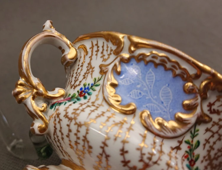 Zbliżenie na boczną ściankę porcelanowego naczynia z widocznym precyzyjnym detalem ręcznie malowanej girlandy z kwiatów