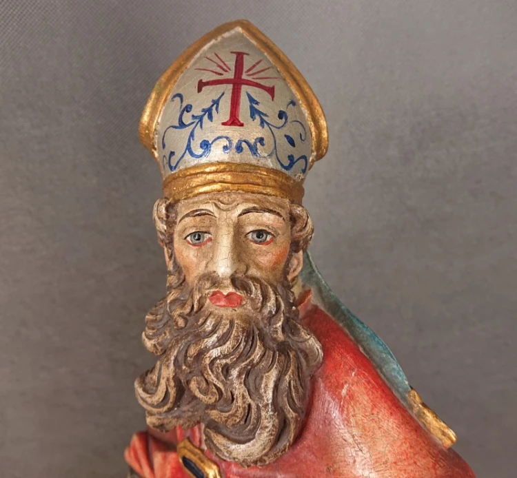 Portretowe ujęcie twarzy Świętego Mikołaja w ozdobnej mitrze z krzyżem, ujęcie od przodu.