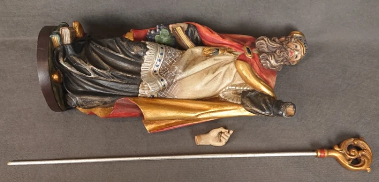 Drewniana rzeźba w pozycji leżącej na boku prezentująca odłączony pastorał oraz ruchomą dłoń.