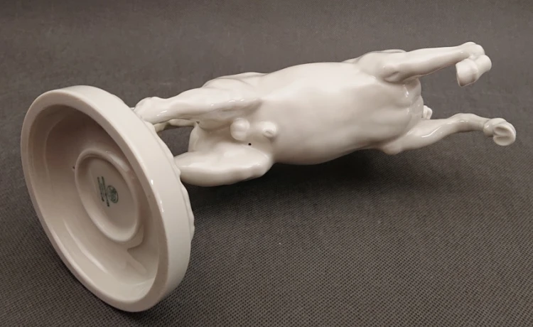 Widok na leżącą rzeźbę konia od dołu, prezentujący konstrukcję podstawy oraz spód porcelanowego obiektu.