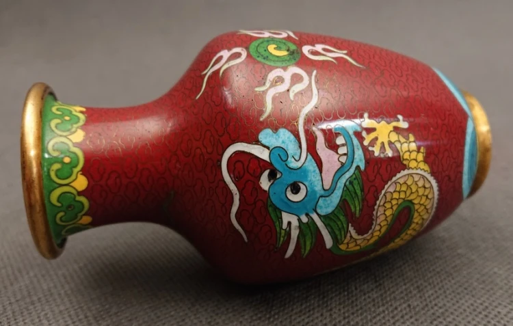 Wazon cloisonne ze smokiem sfotografowany w pozycji leżącej, eksponujący połysk emalii, złocony rant wylewki i profil brzuszka.