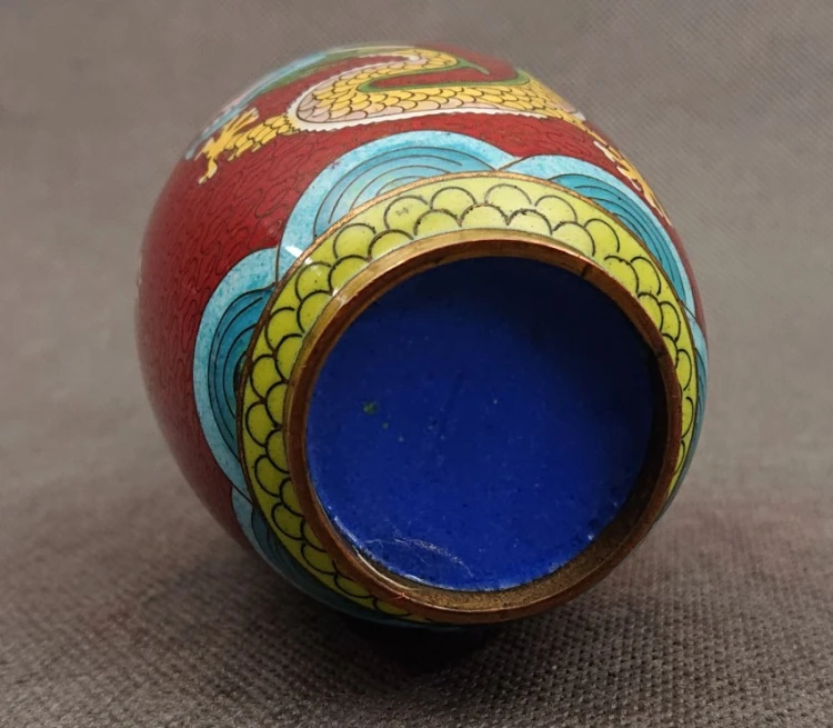 Spód miniaturowego wazonu cloisonne pokryty gładką emalią w intensywnie niebieskim kolorze, otoczony miedzianym rantem podstawy.