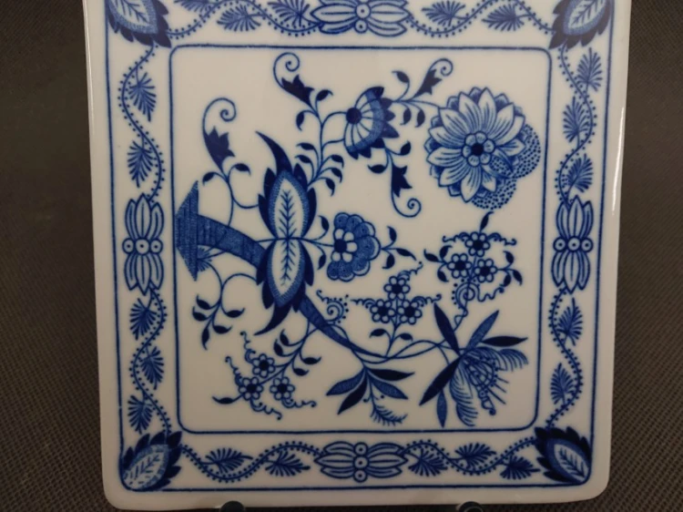 Zbliżenie na dolną, kwadratową część porcelanowej deski kuchennej, przedstawiające precyzyjny, kobaltowy motyw florystyczny ze wzorem cebulowym
