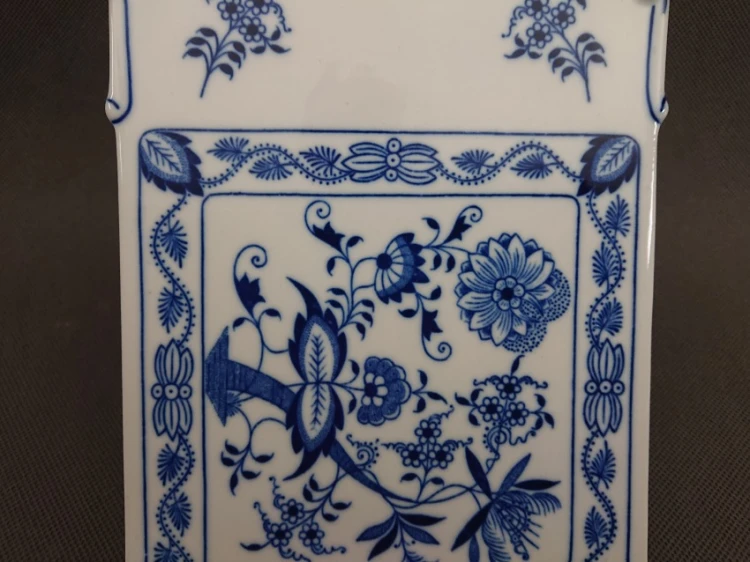 Zbliżenie na dolną, kwadratową część porcelanowej deski kuchennej, przedstawiające precyzyjny, kobaltowy motyw florystyczny ze wzorem cebulowym