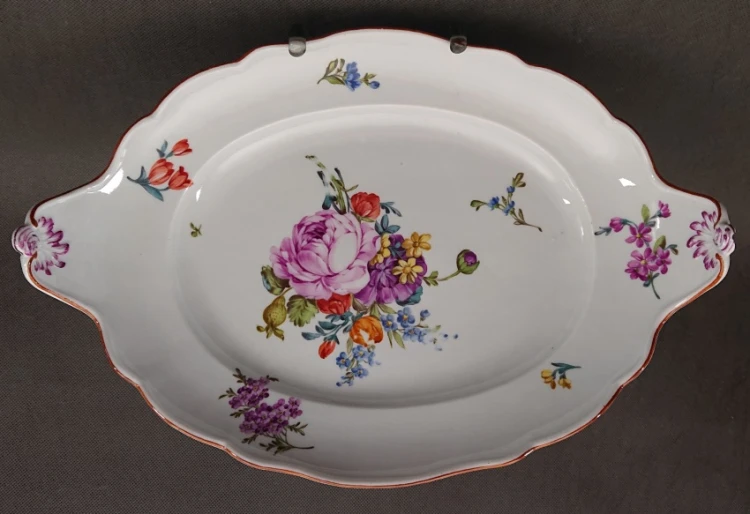 Półmisek porcelanowy obrócony w poziomie, prezentujący bogatą malaturę florystyczną Meissen Flower, czyste białe szkliwo oraz symetryczne, ozdobne uszy.