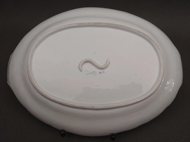 Całościowy widok na spód owalnego półmiska porcelanowego, widoczny nieszkliwiony pierścień podstawy, niebieskie oznaczenia oraz centralna wypustka w kształcie litery S.