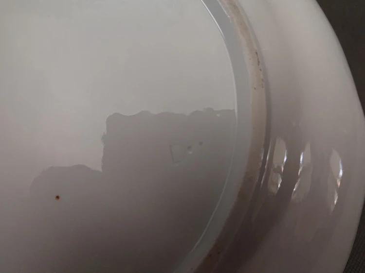 Zbliżenie na dno porcelany z widocznym, wyciśniętym w masie oznaczeniem fabrycznym w postaci litery D oraz dwóch kropek.