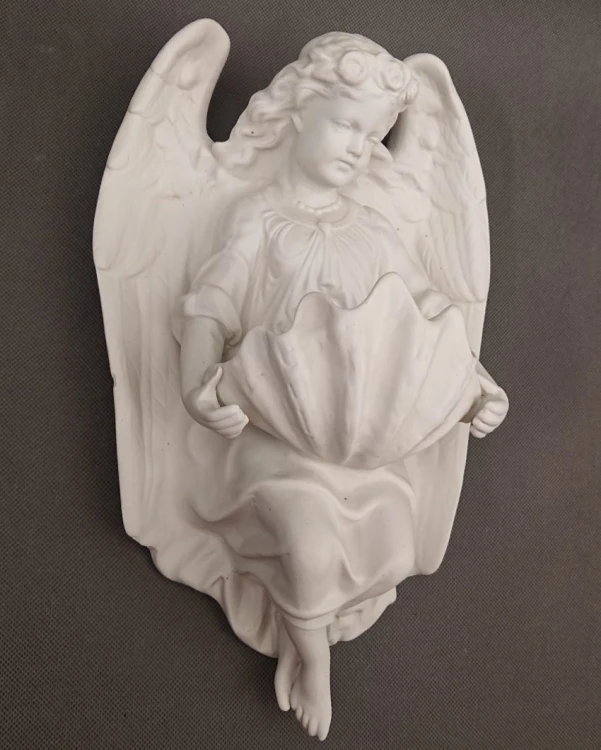 Porcelanowa kropielnica ścienna w ujęciu z lewej strony, podkreślająca precyzyjną strukturę piór na skrzydłach oraz ułożenie szat.