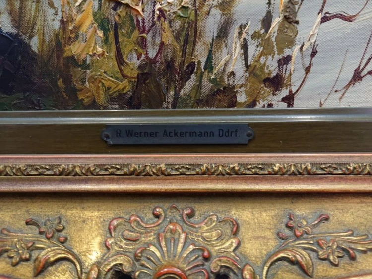 Zbliżenie na dolną krawędź ramy z metalową tabliczką R. Werner Ackermann Ddrf. i sztukaterią