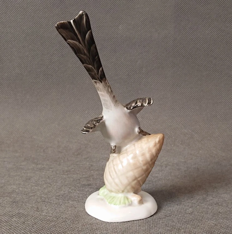 Ujęcie od przodu ręcznie malowanej porcelanowej figurki ptaka na szyszce