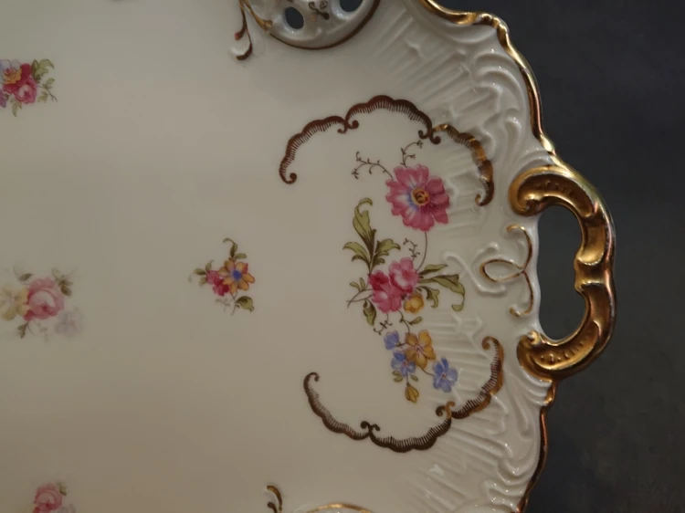 Zbliżenie na złocony uchwyt i kwiatową dekorację kołnierza patery Rosenthal Moliere