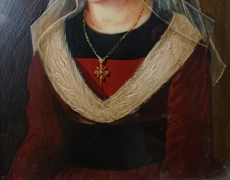 Detal misternie malowanego naszyjnika ze złoconym krzyżykiem i jasnego kołnierza