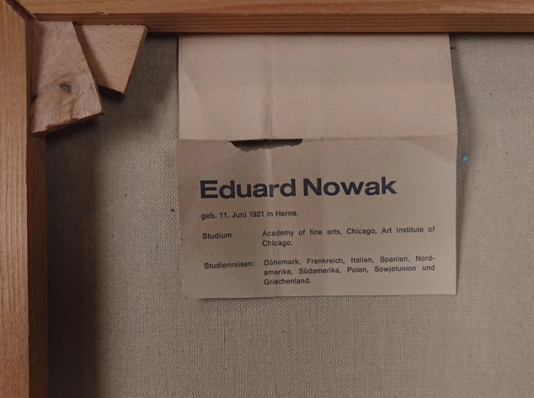 Zbliżenie na drukowaną etykietę biograficzną Eduarda Nowaka na odwrociu krosna malarskiego